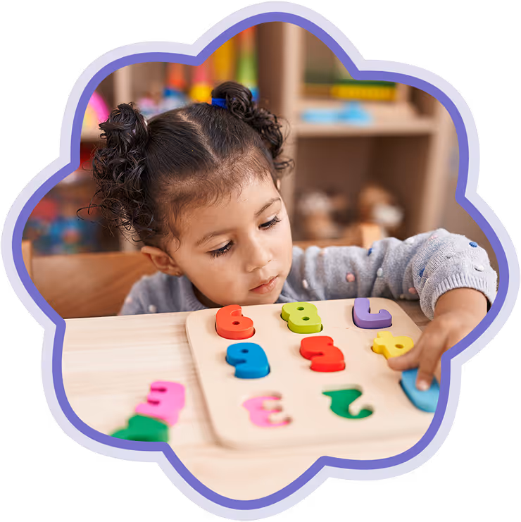 Young child with curly hair focused on placing colorful number puzzle pieces into a wooden board.